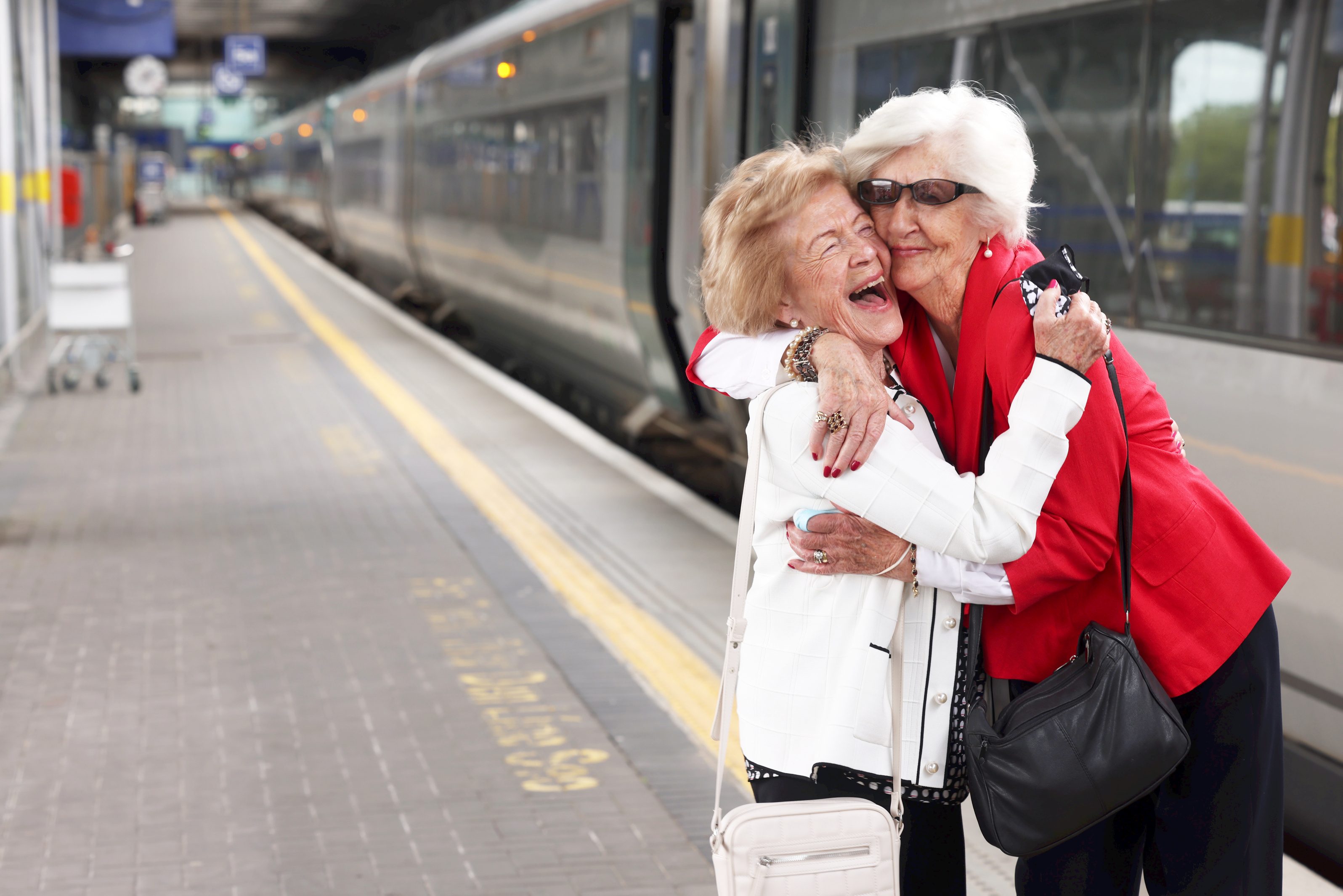 Two female customers hugging before they board the train